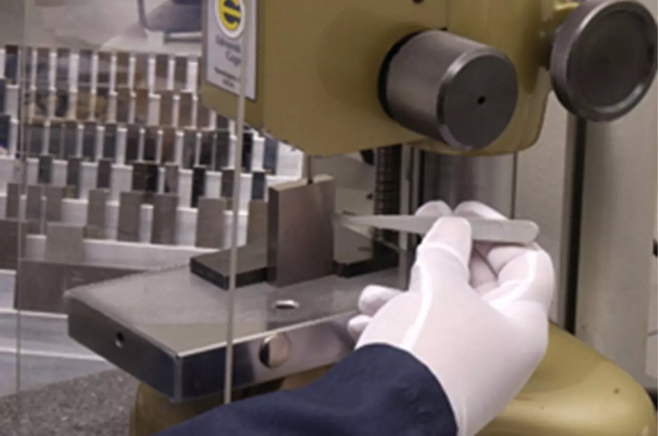 Gloved hand poking tweezers into CMM
