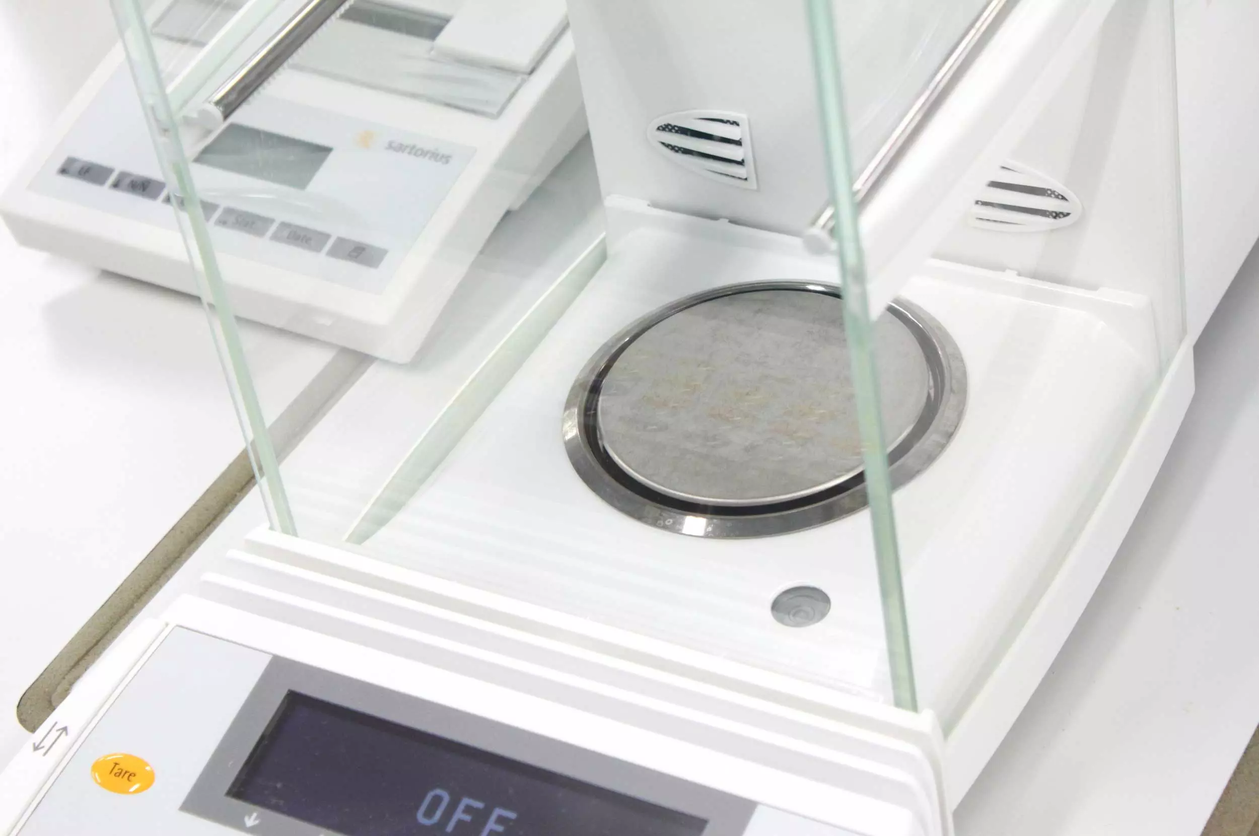 Balance weight machine with metal platform enclosed in glass box.
