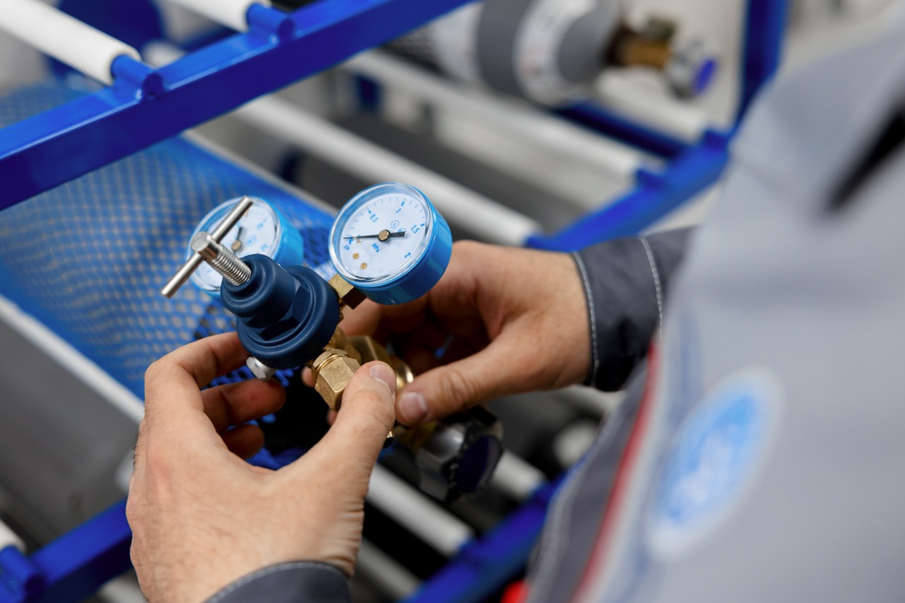 A technician adjusts a pressure regulator attached to gas cylinders, focusing on precision measurements.