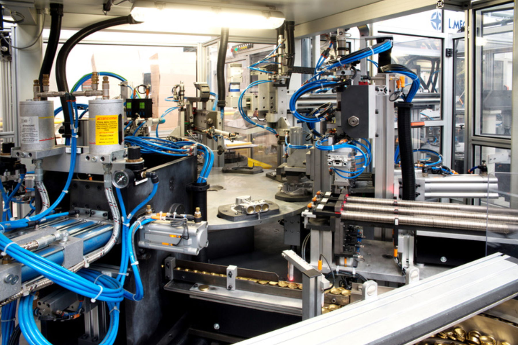 A modern automated manufacturing cell filled with precision industrial equipment. Pneumatic lines, sensors, and mechanical assemblies are integrated into a rotary indexing system, highlighting high-volume production, automation, and advanced engineering processes in a factory environment.