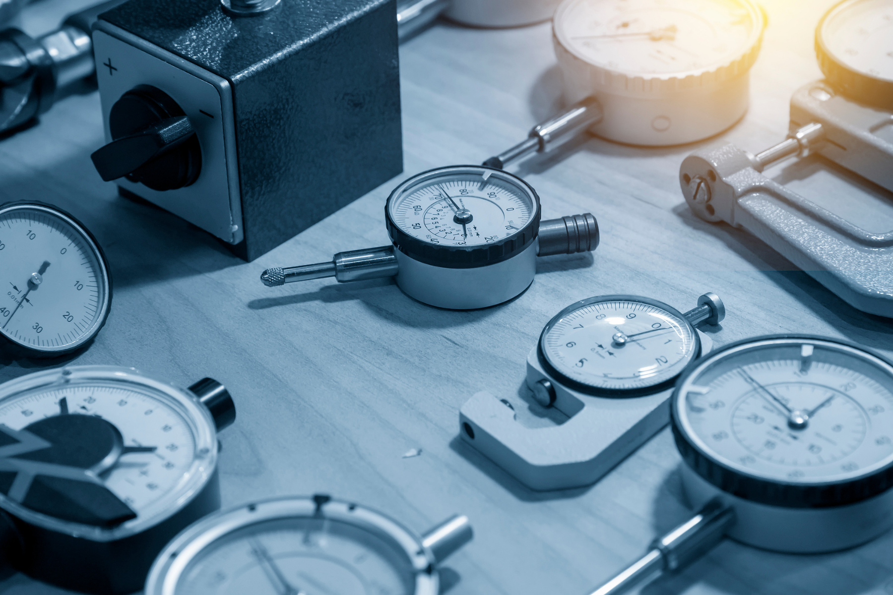 A collection of dial indicators and calibration instruments arranged on a workbench, showcasing the variety of tools used for precise dimensional measurement and quality control.