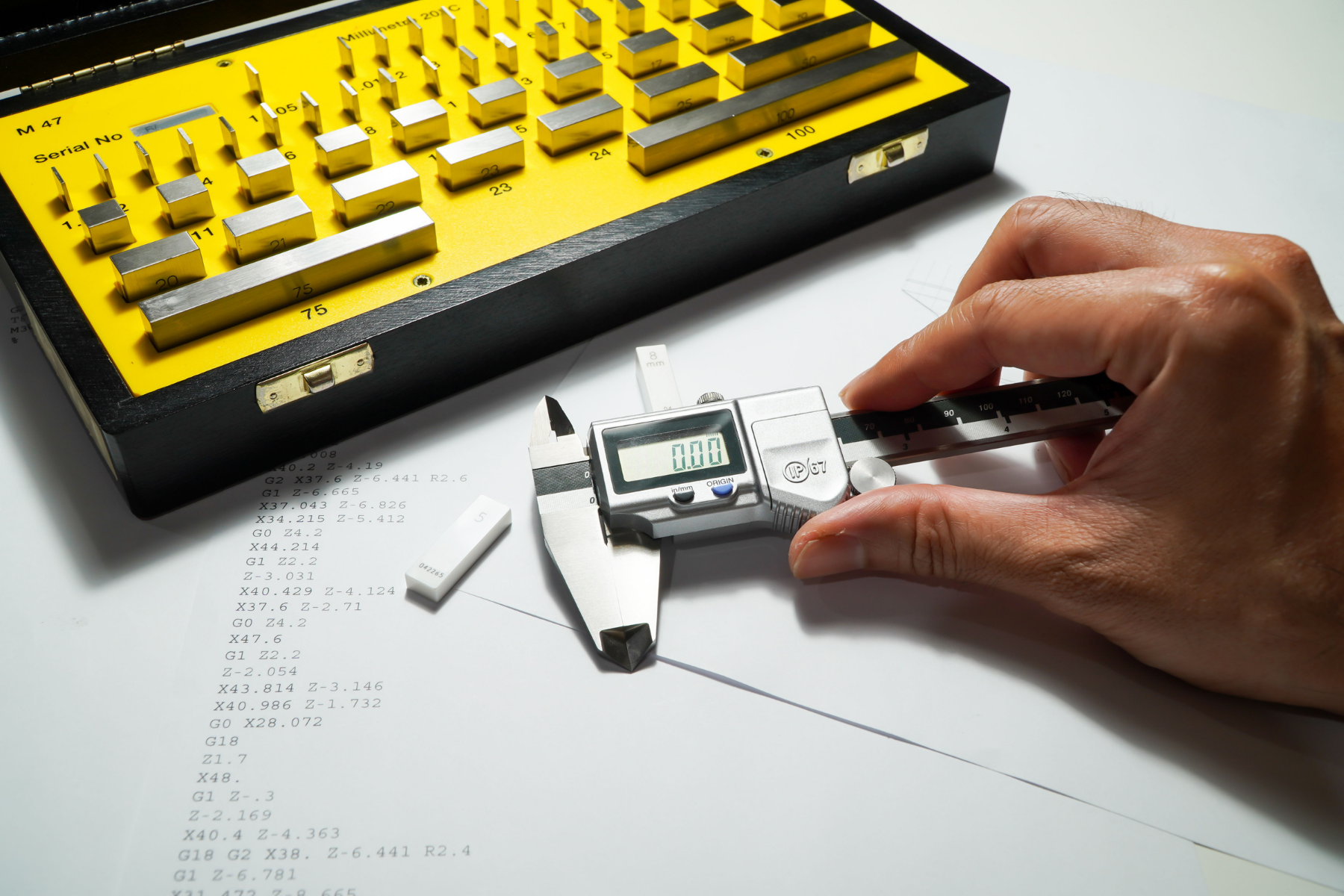A digital caliper measures a small component beside a set of gauge blocks, illustrating practical measurement techniques used to verify accuracy and ensure compliance with specifications.