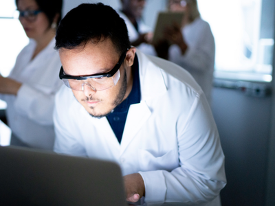 Scientist observing laptop, analyzing data.